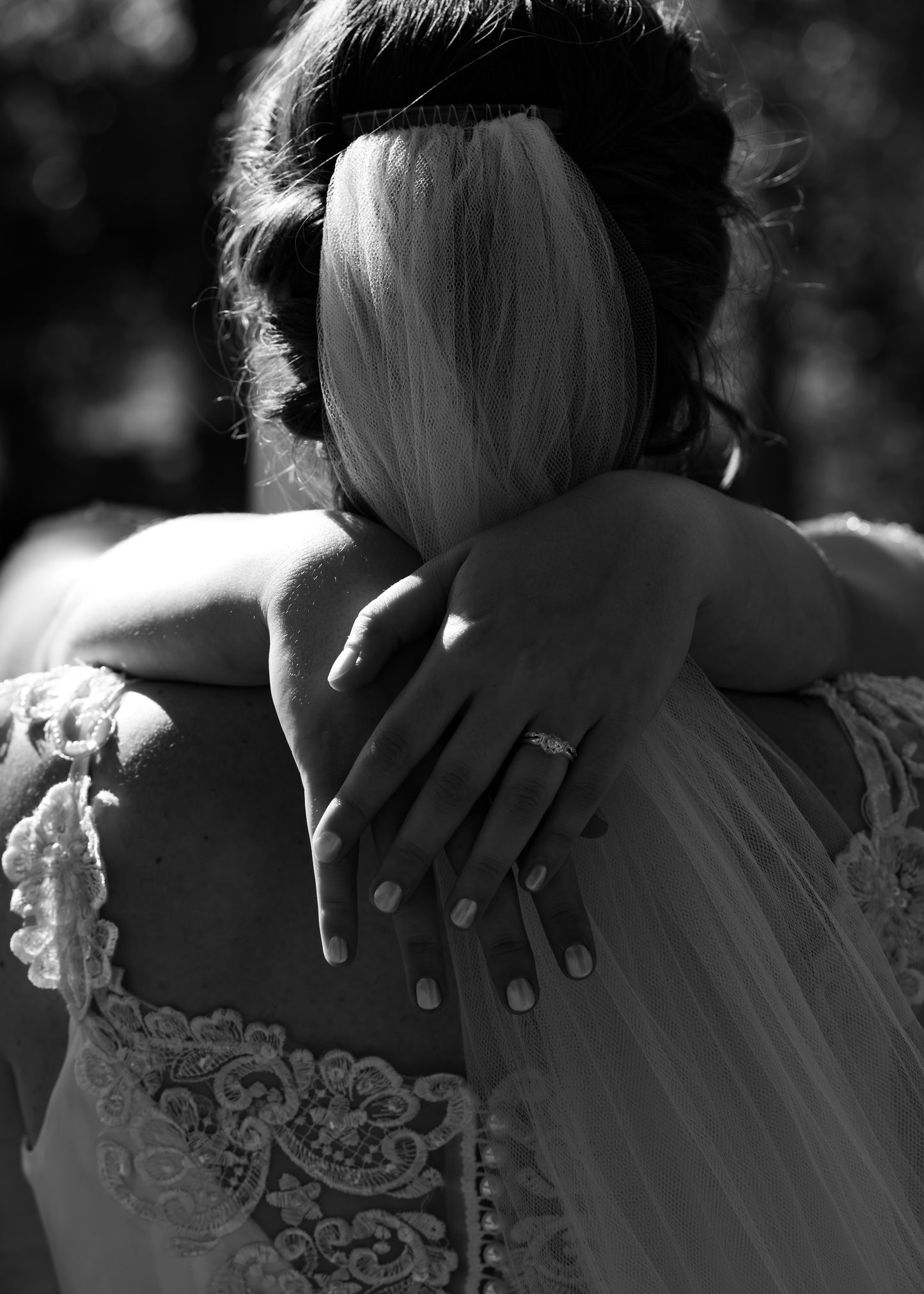 Black and white photo of a person in a wedding dress with another person's hand on their shoulder.