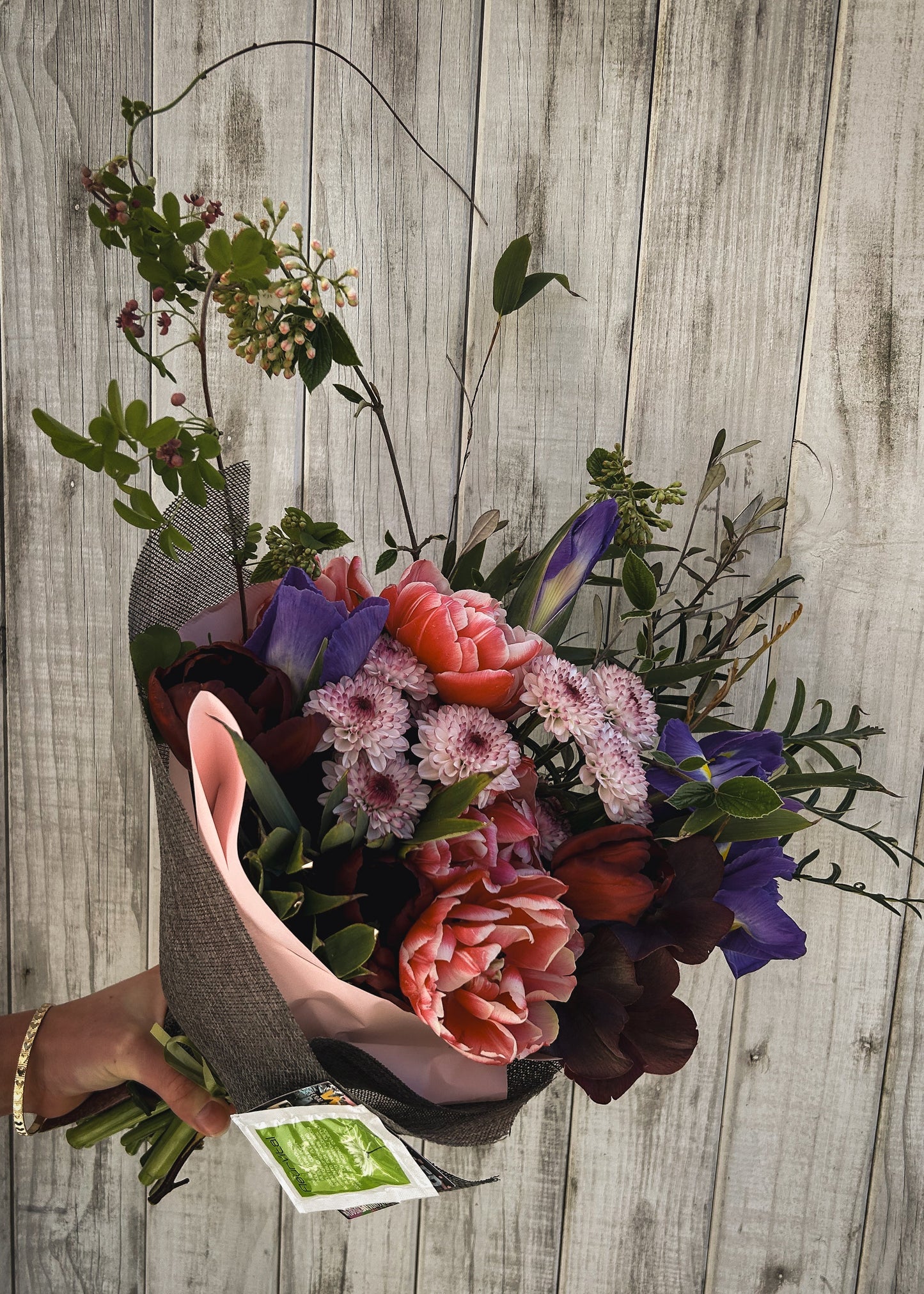 Bouquet of flowers held by a hand on a wooden surface