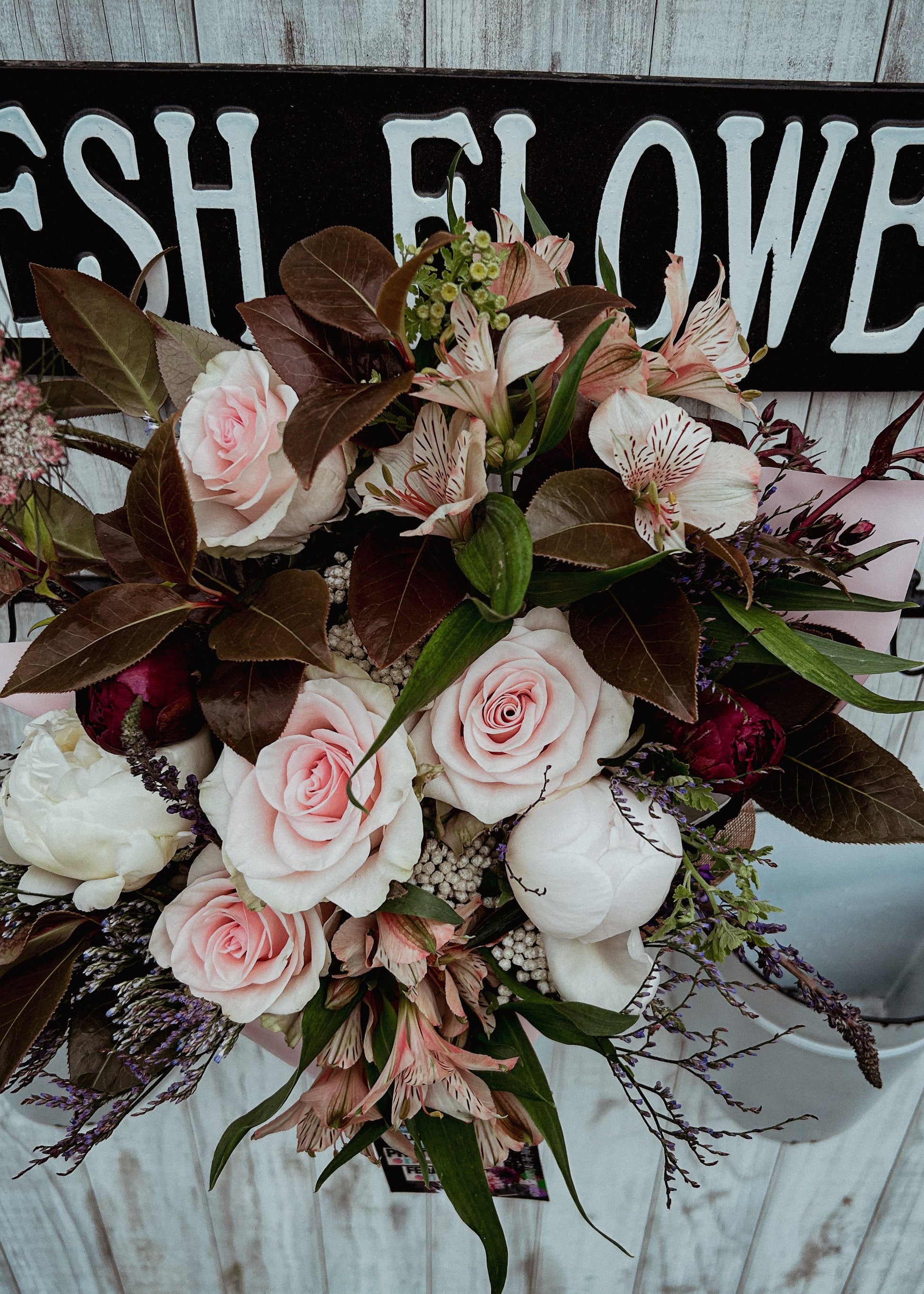 Floral arrangement with a 'Fresh Flowers' sign in the background
