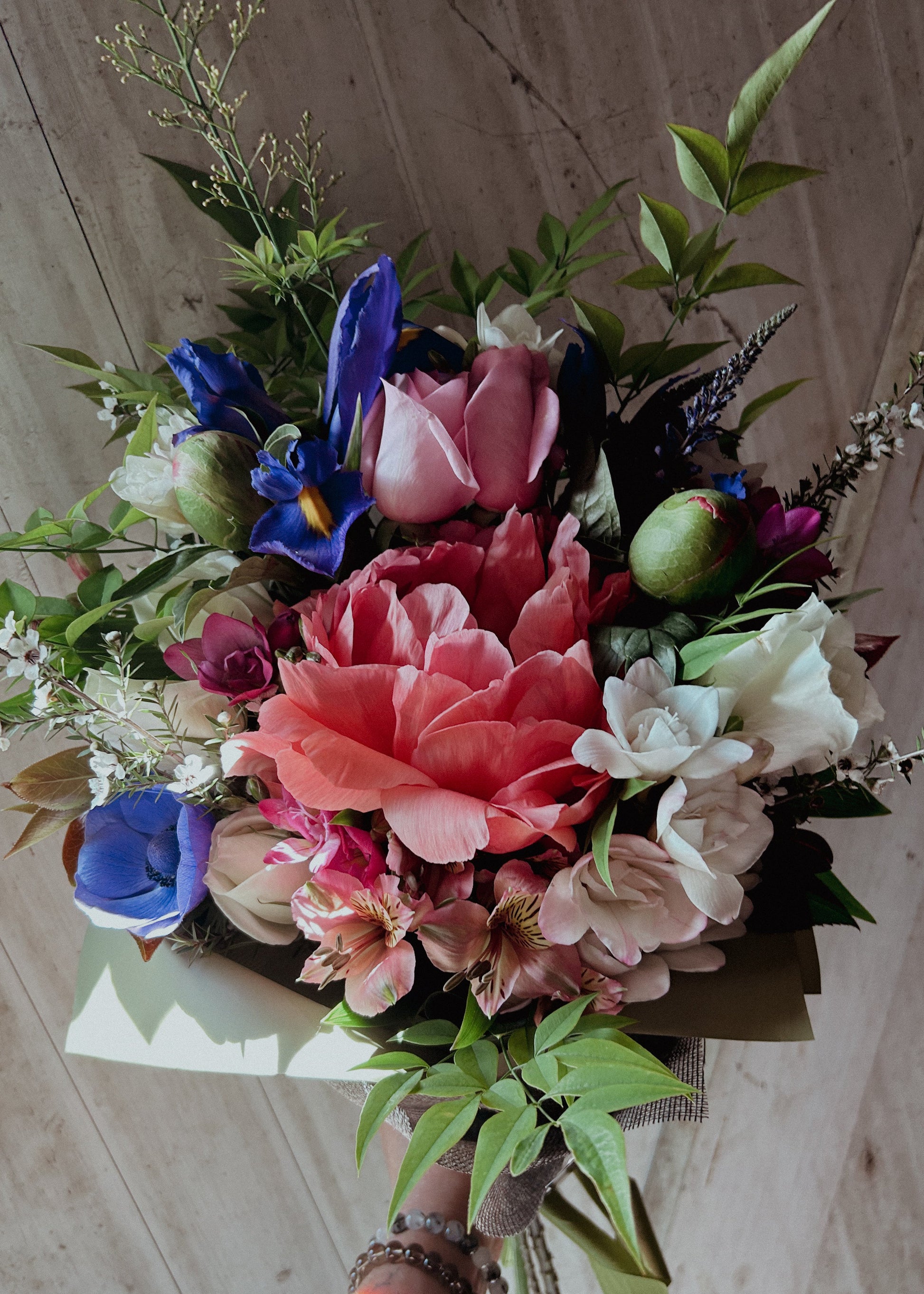 Bouquet of colorful flowers with pink, blue, and green tones on a wooden background
