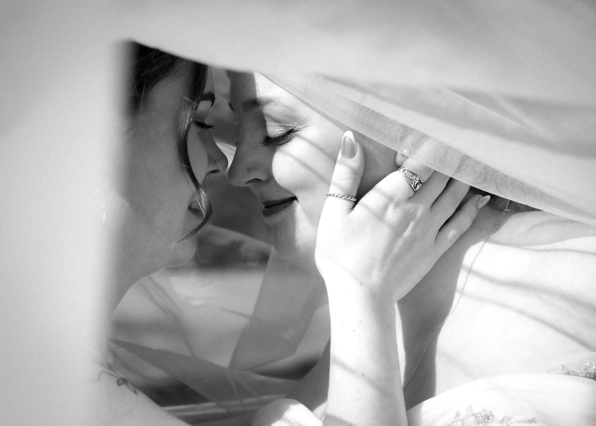 Black and white photo of a couple embracing under a blanket
