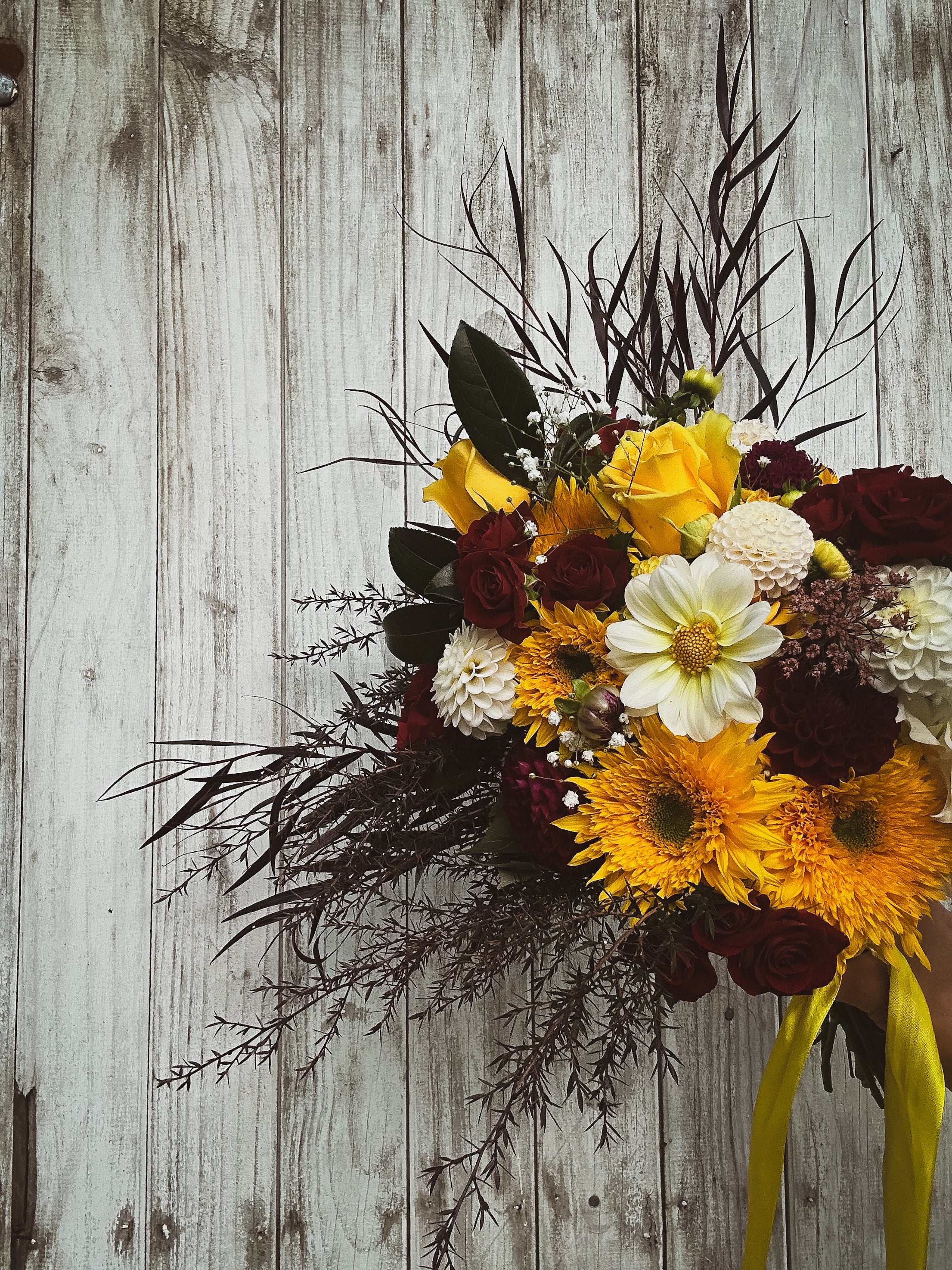 Wildstyler wedding bouquet with bright sunflowers and deep red roses. Wild textures for a statement bridal bouquet. Koputaroa, NZ